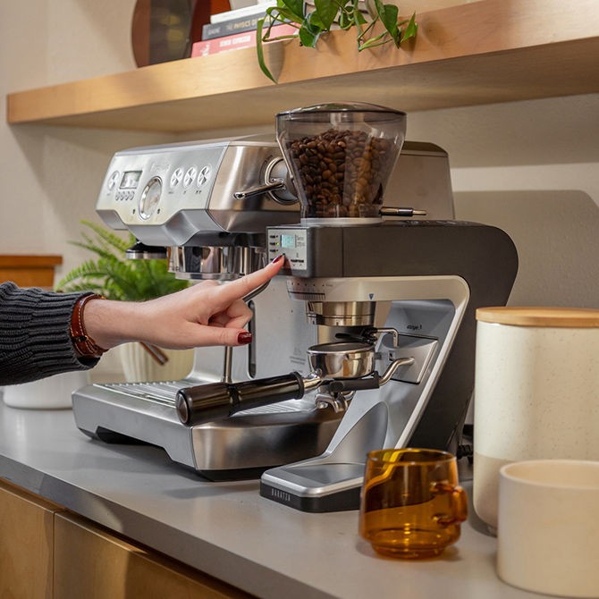 Pouring coffee from a perculator to a mug on top of a wooden benchtop.